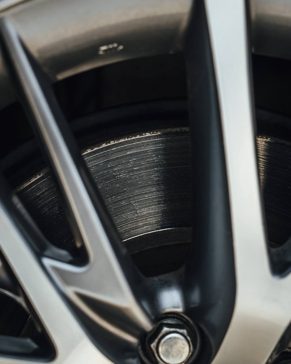 Close-up of an alloy spoke and brake disc with light marks on the metal, not a kerb-rashed diamond-cut lip